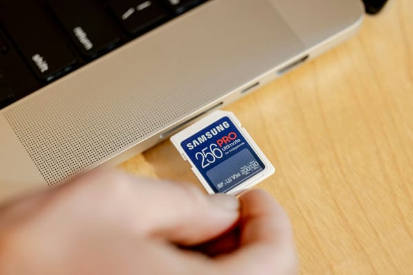 Pessoa segurando cartão de memória ao lado de notebook, ilustrando organização de arquivos digitais